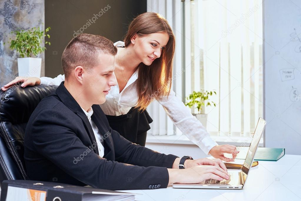 Happy executive or secretary giving documents to a businessman in a desktop at office