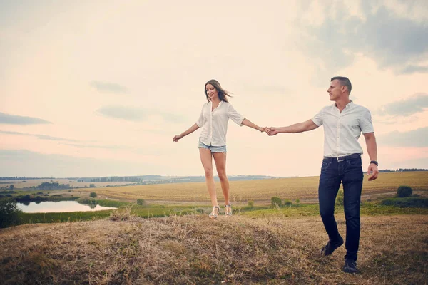 Casal feliz de mãos dadas e caminhando juntos ao ar livre ao pôr do sol — Fotografia de Stock