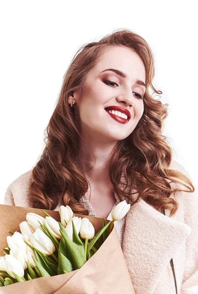 Hermosa chica en un abrigo con flores tulipanes en las manos sobre un fondo claro — Foto de Stock