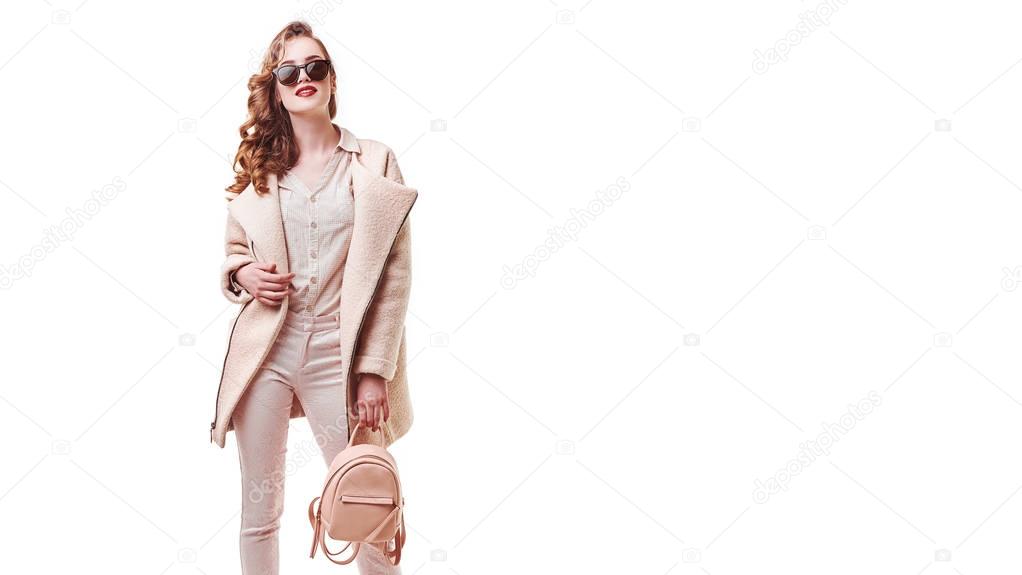 Woman Style And Fashion Clothes. Female Model Wearing Stylish Fashionable Clothing, Light Pink Coat, Purple Backpack Bag On White Background. Beautiful Girl Posing In Studio Portrait. High Resolution