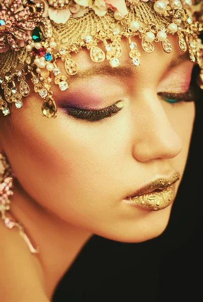 Peinado y maquillaje. Pendientes de oro. Belleza Chica modelo de moda con maquillaje dorado, maquillaje de piel dorada, cabello y joyas sobre fondo negro . — Foto de Stock