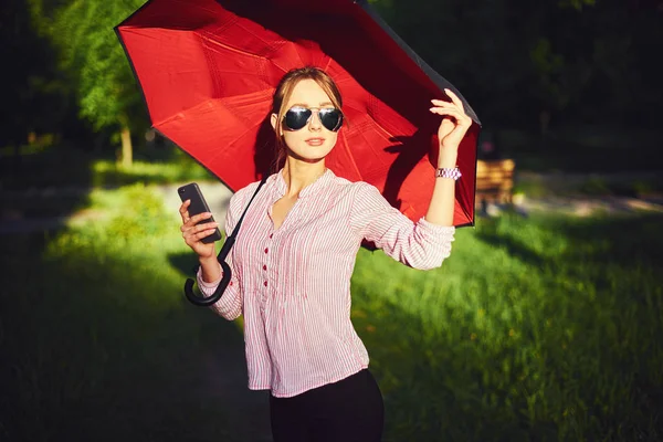 Frau telefoniert auf der Straße unter einem Regenschirm — Stockfoto