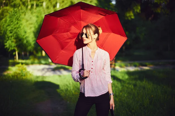 Beautiful young lady holding multicolored umbrella. Blue sky outdoors. Happy girl on countryside landscape — Stock Photo, Image