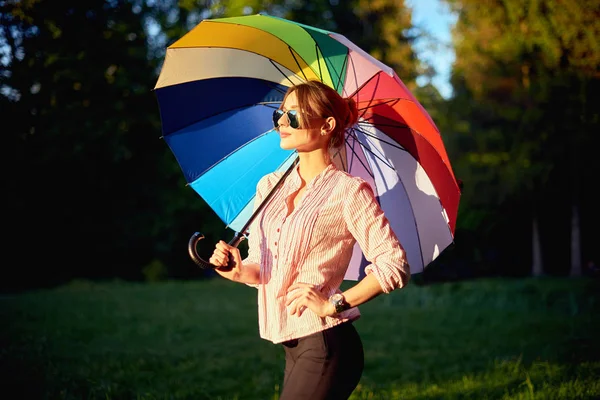 Schöne junge Dame mit buntem Regenschirm. blauer Himmel im Freien. glückliches Mädchen auf dem Land — Stockfoto