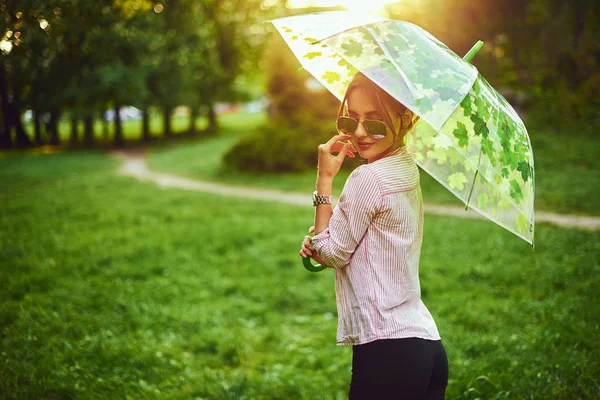 Menina bonita segurando guarda-chuva multicolorido. Céu azul ao ar livre. Menina feliz na paisagem rural — Fotografia de Stock