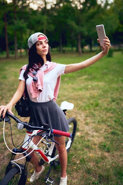 Park bisiklet sürme ile akıllı telefon kullanan genç kadın