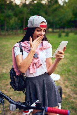 Park bisiklet sürme ile akıllı telefon kullanan genç kadın