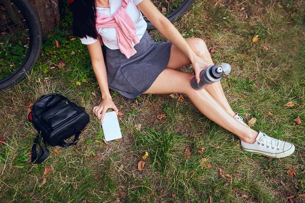 若い女性が公園で自転車に乗るとスマート フォンを使用して — ストック写真