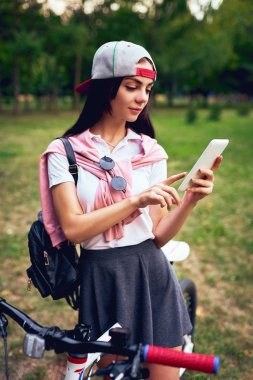 Park bisiklet sürme ile akıllı telefon kullanan genç kadın