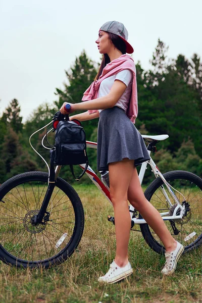 Gün batımında ormandaki bir bisiklet sürme sonra genç kadın içme suyu