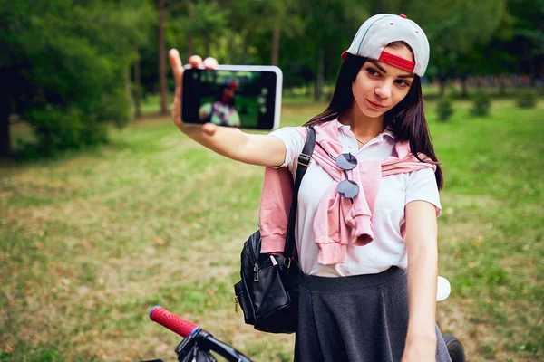 Молодая женщина с помощью смартфона с велосипедом в парке — стоковое фото