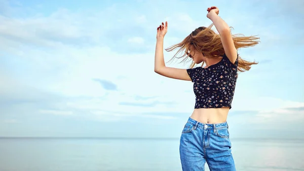 Party girl dancing and waving hands on the beach over blue sky — Stock Photo, Image