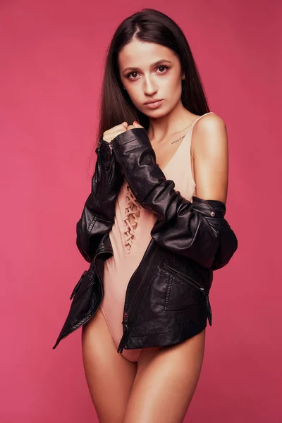 Modèle en body rose. gracieuse jeune femme en veste noire debout isolé sur fond lumineux Images De Stock Libres De Droits