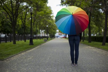 parkta sokakta duran bir adam renkli bir şemsiye ile.