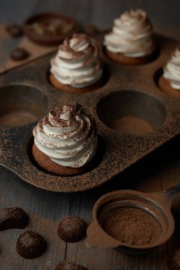 Beyaz kremalı kek pişirme için demir formdaki kakao serpilir