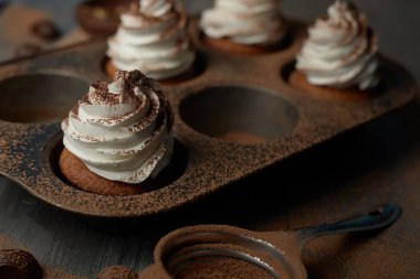 Beyaz kremalı kek pişirme için demir formdaki kakao serpilir