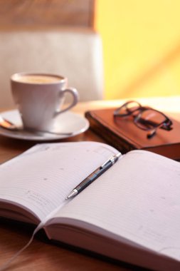 Kapuçino gözlüklerle coffee House ahşap bir masa üzerinde bir günlük kulplu kahve ile bir daire ile kupa