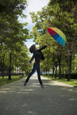 Bir kız bir deri ceket ve kot renkli bir şemsiye ile sokakta üzerinde atlar.