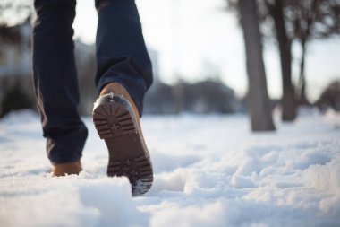 Kırmızı ayakkabılar ve gri kot bir adam Karda yürüyor