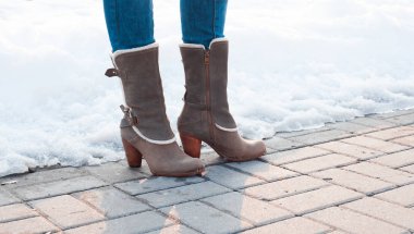 Gri beyaz kürklü topuklu çizme ve kaldırım taşları ile kar üzerinde tokalar