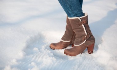 Gri beyaz kürklü topuklu çizme ve kar üzerinde tokalar