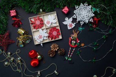 Siyah arka planda kırmızı toplar, yıldızlar, çanlar ve kar taneleri olan Noel oyuncakları ve süslemeleri