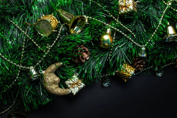 Christmas wreath decorated with golden balls, bells, gifts and decorative reels on a black background