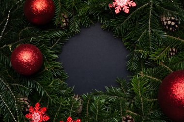 Dekoratif kar taneleri ve oyuncaklarla süslenmiş Noel çelengi. Siyah arka planda metin için yer var. Boşluğu kopyala