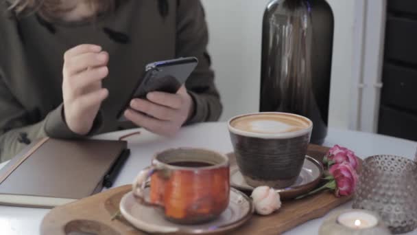 Dziewczyna Trzymająca Telefon Rękach Przewijająca Kartki Siedząc Przy Stole Kawą — Wideo stockowe