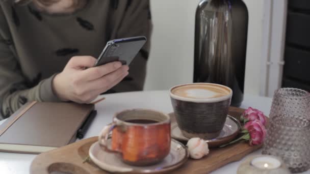 Dívka Drží Telefon Ruce Rolování Stránky Zatímco Sedí Stolu Kávou — Stock video