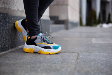 Ayakkabı ayakkabısı, spor ayakkabısı, çok renkli sarı, beyaz, siyah ve mavi mermer bir duvara yerleştirilir.