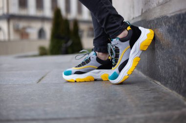 Ayakkabı ayakkabısı, spor ayakkabısı, çok renkli sarı, beyaz, siyah ve mavi mermer bir duvara yerleştirilir.