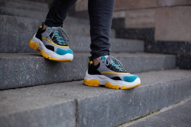 Ayakkabılar içinde ayaklar, çok renkli sarı, beyaz, siyah ve mavi mermer merdivenlerden aşağı.