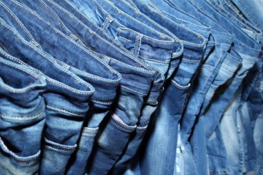 Arka planda mavi renkli kot pantolon yığını.