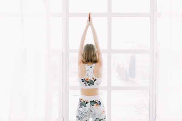 Eşofmanlı bir kız evde spor yapıyor. Egzersiz egzersiz esneme ve yoga.