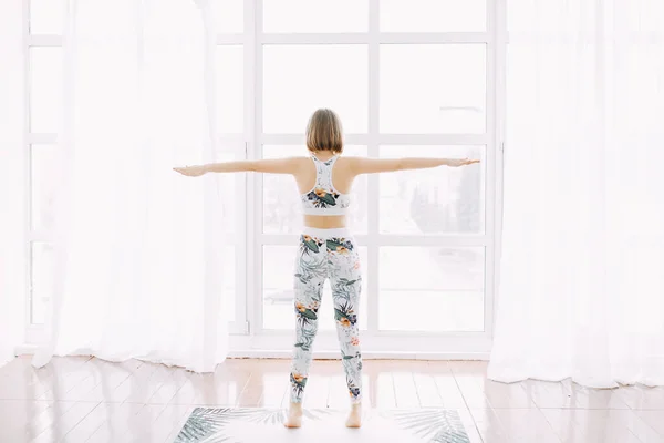 Eşofmanlı bir kız evde spor yapıyor. Egzersiz egzersiz esneme ve yoga.