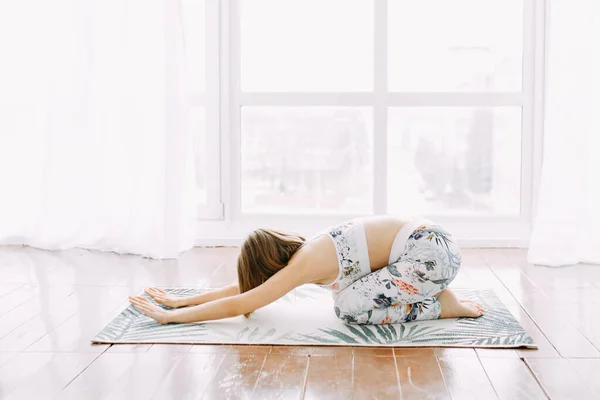 Eşofmanlı bir kız evde spor yapıyor. Egzersiz egzersiz esneme ve yoga.