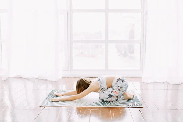 Eşofmanlı bir kız evde spor yapıyor. Egzersiz egzersiz esneme ve yoga.