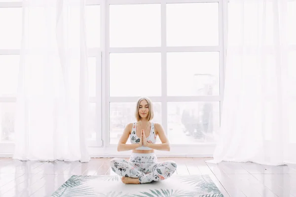 Eşofmanlı bir kız evde spor yapıyor. Egzersiz egzersiz esneme ve yoga.