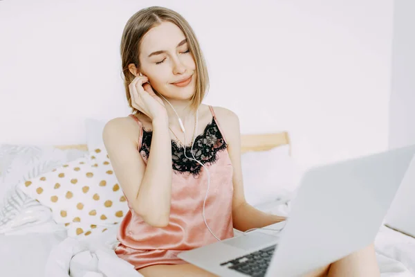 Pembe pijamalı, dizüstü bilgisayarlı, evde, internette, iş yerinde, yatakta uzanan, telefonla konuşan, sipariş, dükkan, parlak iç mekan.