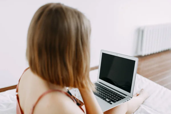 Pembe pijamalı, dizüstü bilgisayarlı, evde, internette, iş yerinde, yatakta uzanan, telefonla konuşan, sipariş, dükkan, parlak iç mekan.