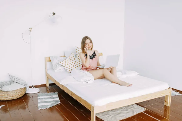 Pembe pijamalı, dizüstü bilgisayarlı, evde, internette, iş yerinde, yatakta uzanan, telefonla konuşan, sipariş, dükkan, parlak iç mekan.