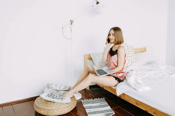 Pembe pijamalı, dizüstü bilgisayarlı, evde, internette, iş yerinde, yatakta uzanan, telefonla konuşan, sipariş, dükkan, parlak iç mekan.