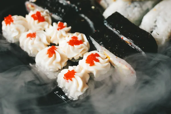 Japon yemek servisi elinde çubuklarla siyah bir arka planda plastik bir kutuda yuvarlanıyor.