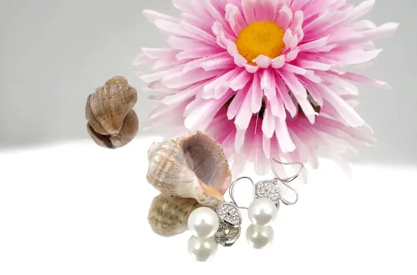 Pearl earrings advertisment - shells and flowers on mirrorlike background — Stock Photo, Image