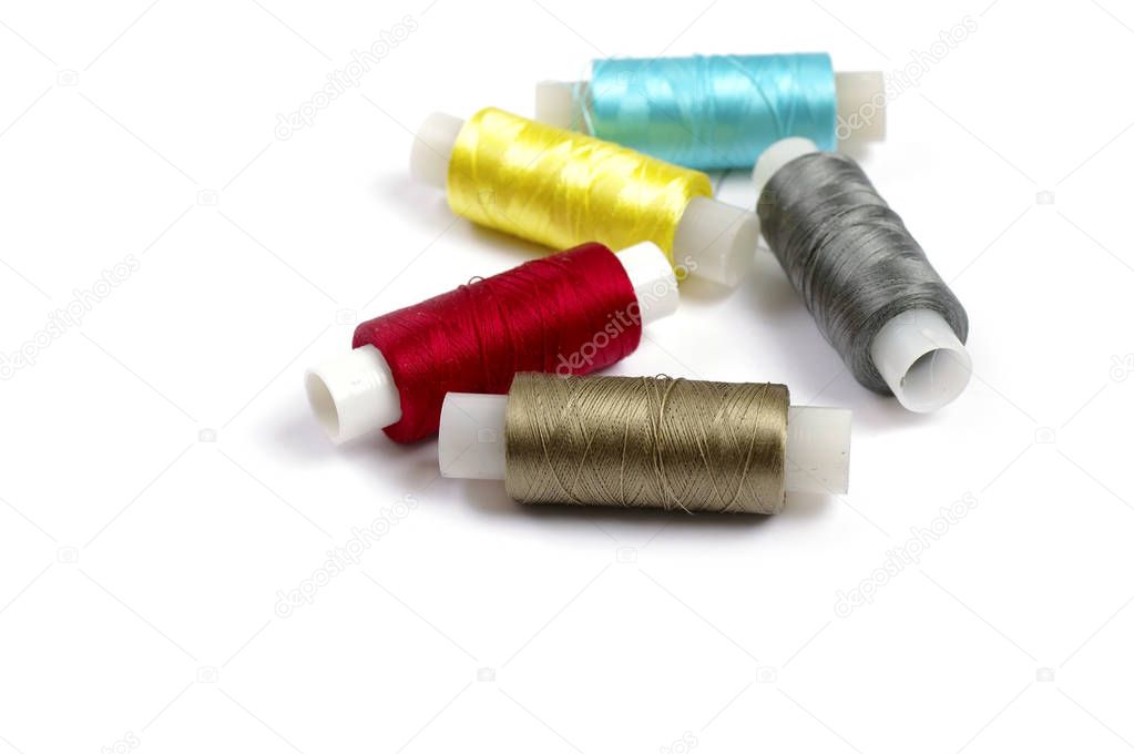 Spools of multicolored silk threads on white background