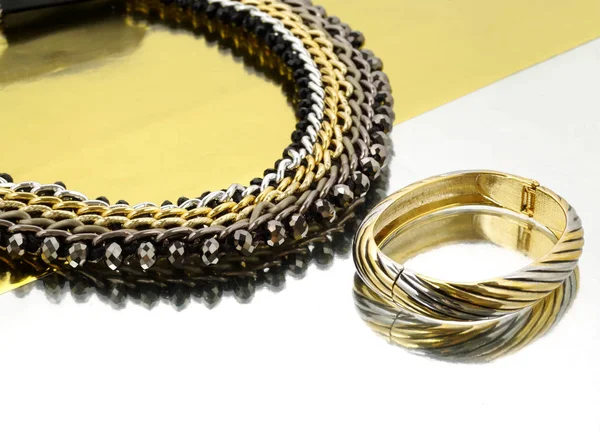 Halsband och armband på golden och silver spegel bakgrund — Stockfoto