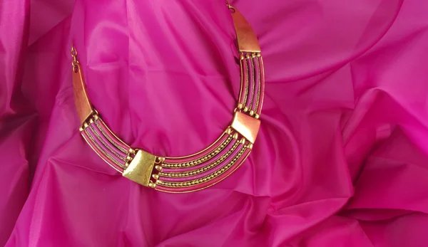 Ярко-розовое ожерелье на розовом текстильном фоне - красновато-модные украшения — стоковое фото