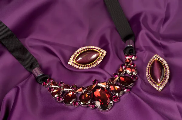 Collier et boucles d'oreilles en verre violet sur fond textile — Photo