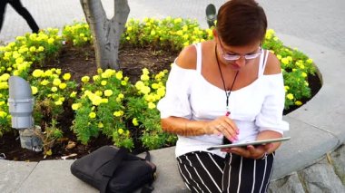 tablet bilgisayar şehir parkında oturan genç kadın